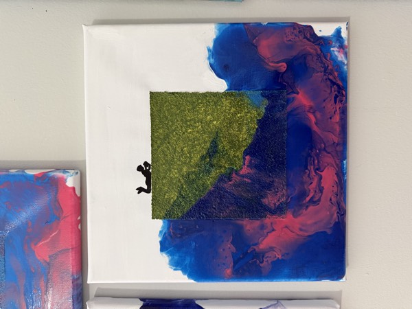 Small square mixed media painting with blue and pink poured paint around a textured green square and a black silhouette of a diver